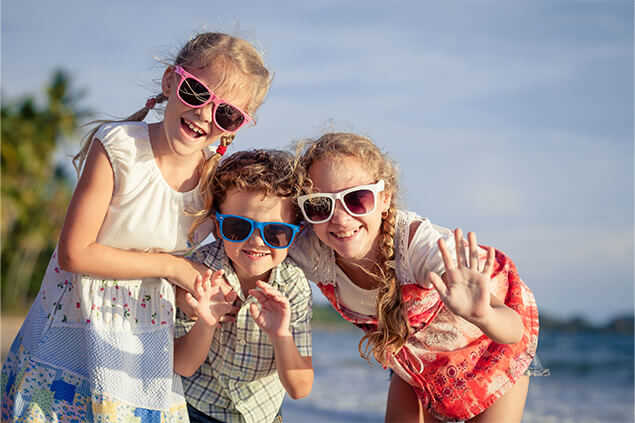 Tres niños con gafas sonriendo en la playa