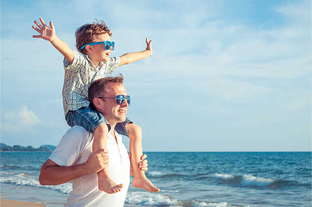 Padre e hijo con lentes caminando por la playa