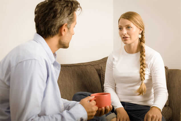 Hombre y mujer sentados en sofa conversando