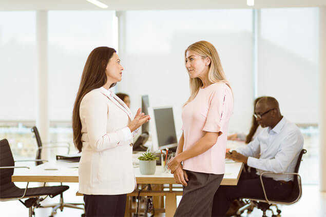 Dos mujeres conversando en entorno laboral