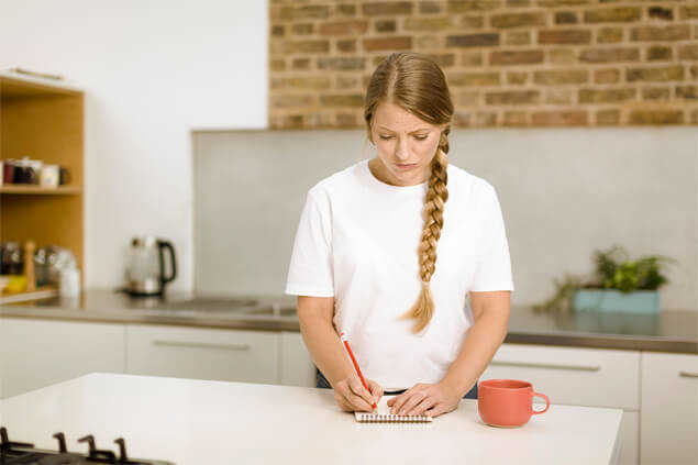 Chica tomando notas con papel y lápiz