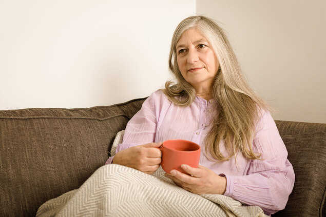 Señora acostada en un sofa cubierta con una manta