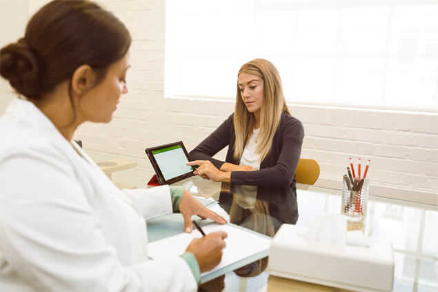 Paciente mujer mostrando archivo de tablet a espacielista