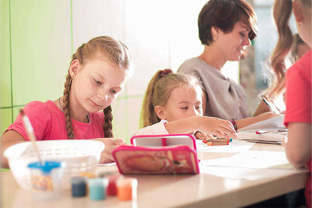 Niñas en mesa de trabajo pintando