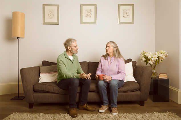 Señores mayores conversando sentados en el sofa