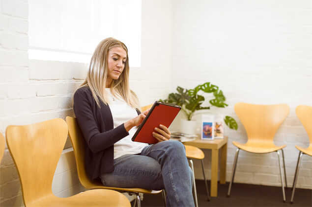 Mujer sentada en sala de espera mirando una tablet