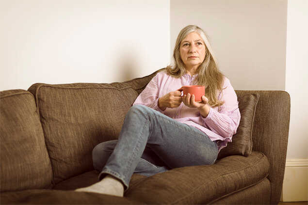 Señora sentada en el sofa con una taza en las manos
