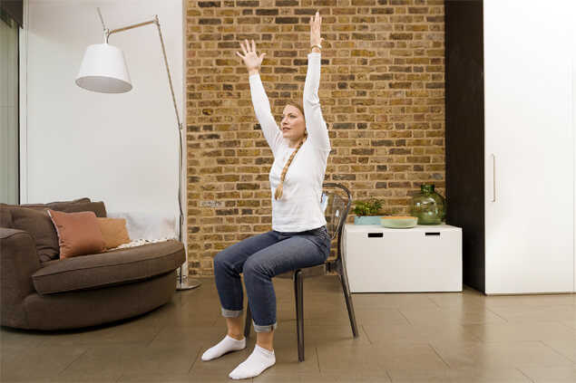 Mujer joven estirando sus brazos sentada en una silla