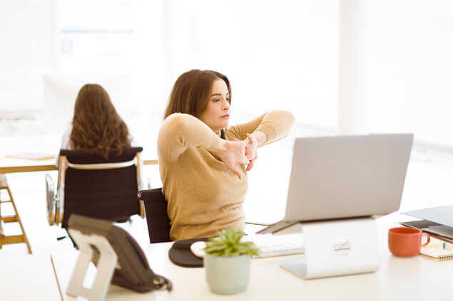 Mujer doblando sus brazos frente a ordenador