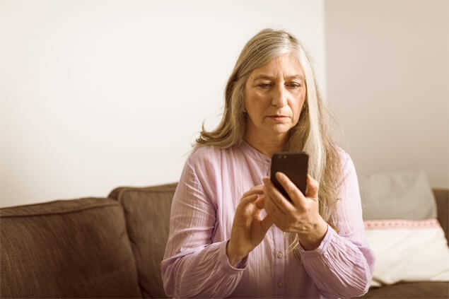 Señora sentada en el sofa viendo el móvil