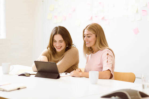 Dos mujeres mirando una tablet riendo