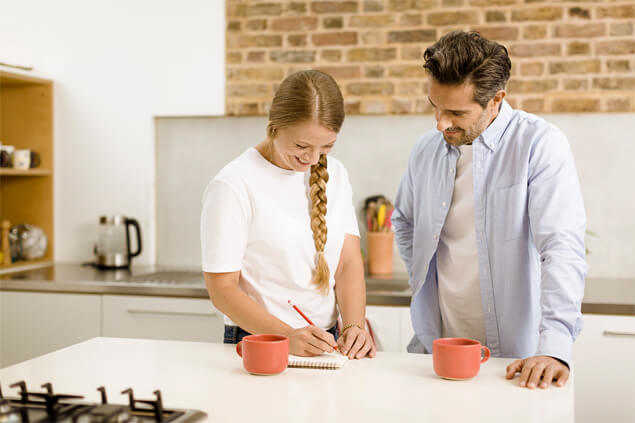 Pareja tomando apuntes en la cocina