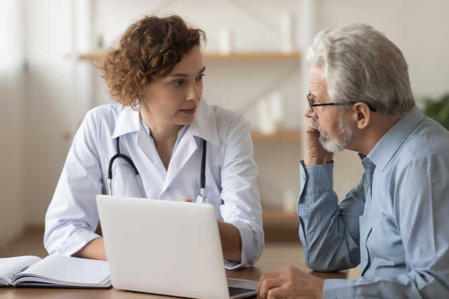 Una doctora habla con un hombre delante de un portatil